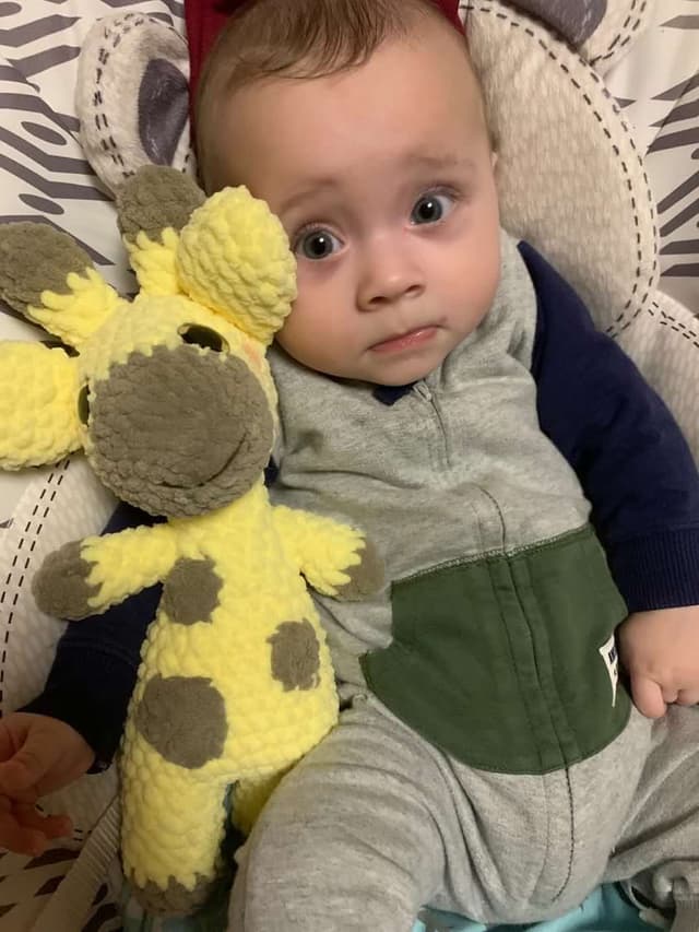 Baby smiling with a handmade crochet giraffe